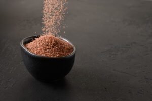 suplementos veganos, Verter sal negra india Kala Namak en un tazón. Útil para vegetarianos como fuente de hierro.